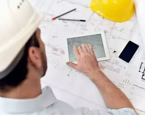 Image shows a man looking at construction drawings on a desk